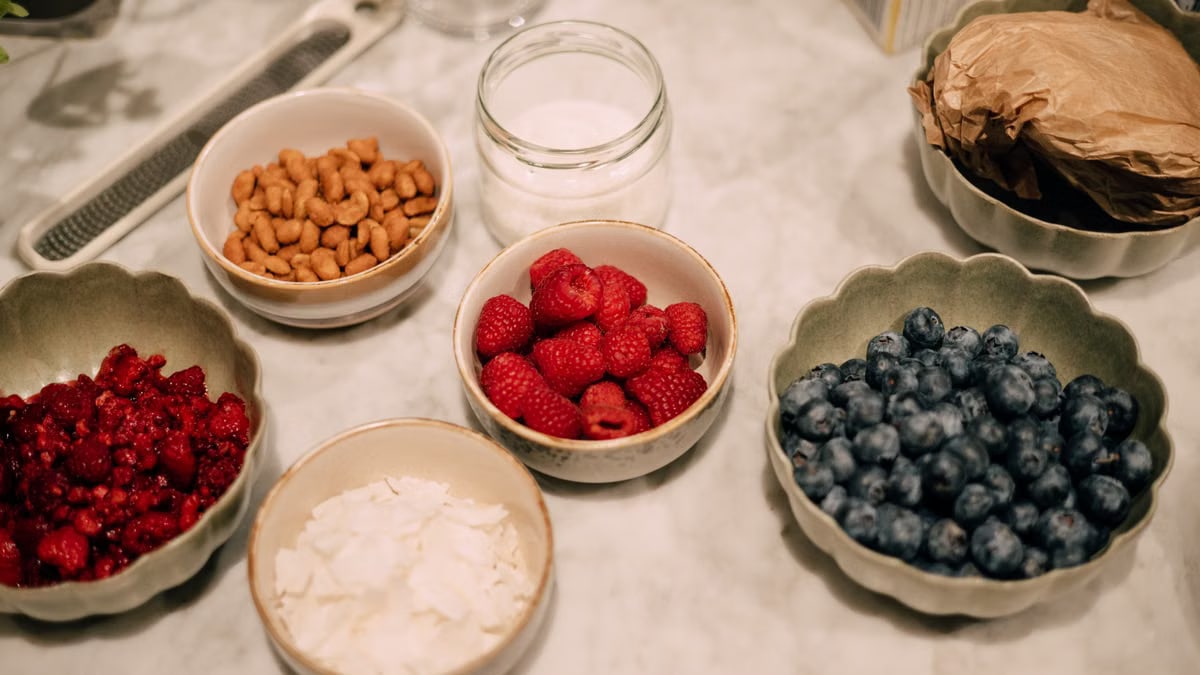 A variety of fresh berries, nuts, and ingredients in bowls perfect for breakfast or food photography.